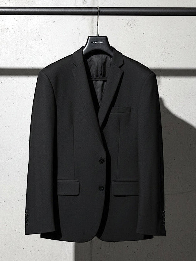 Black suit jacket on a hanger against a light gray wall