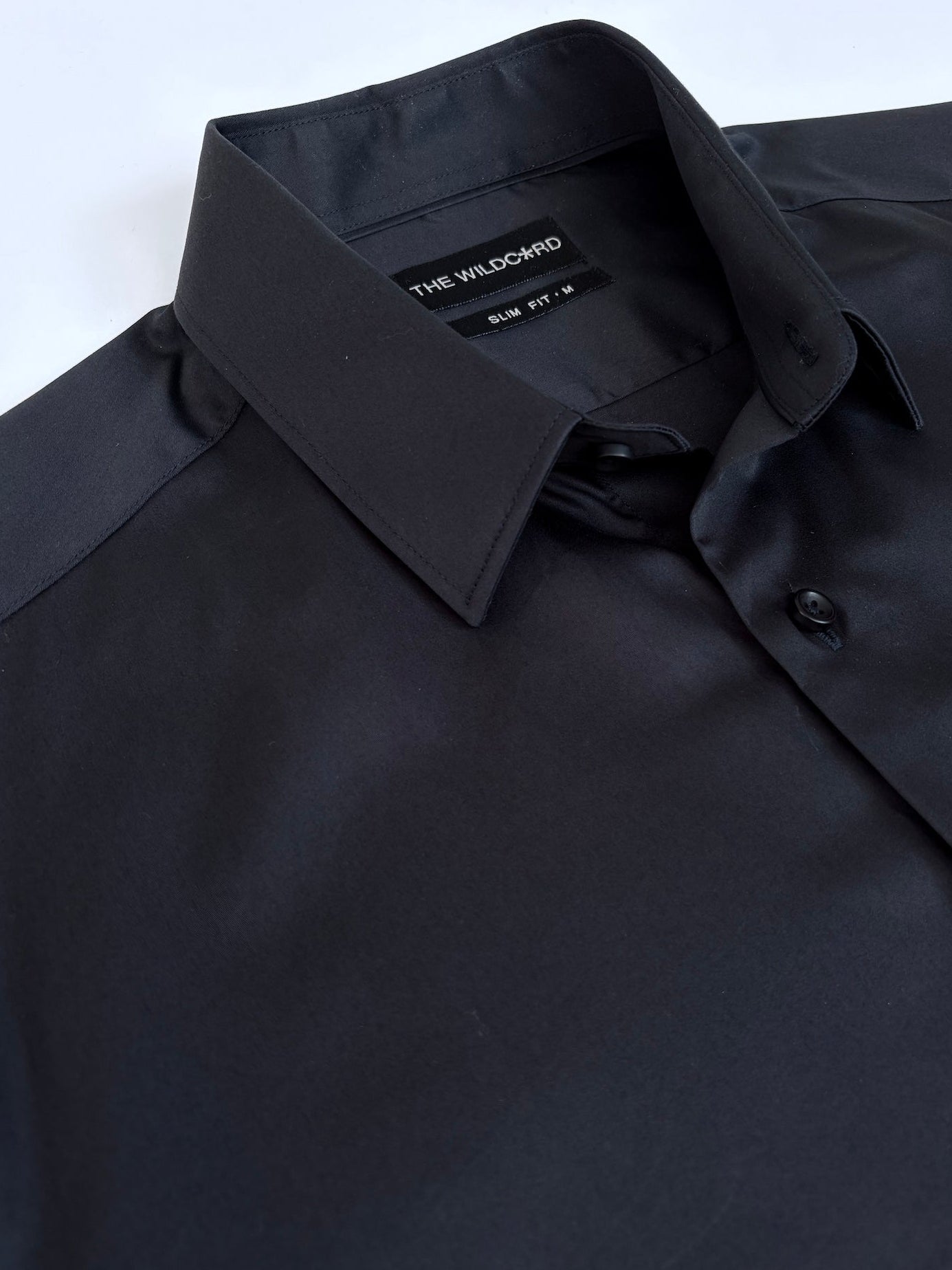 Dark navy dress shirt with collar and label on a white background