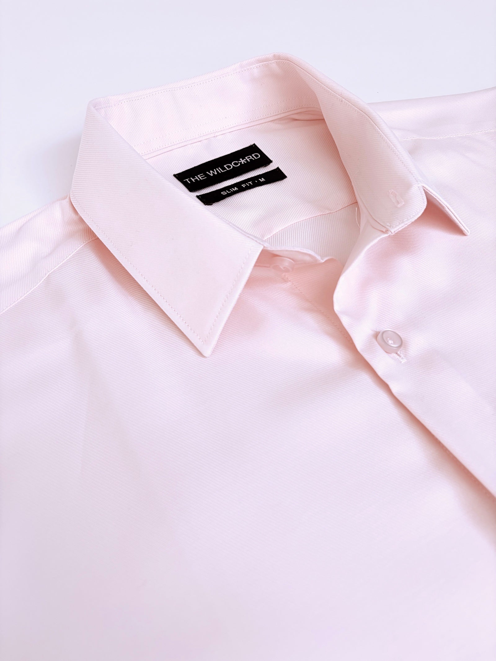 Light pink dress shirt with collar and label on a white background