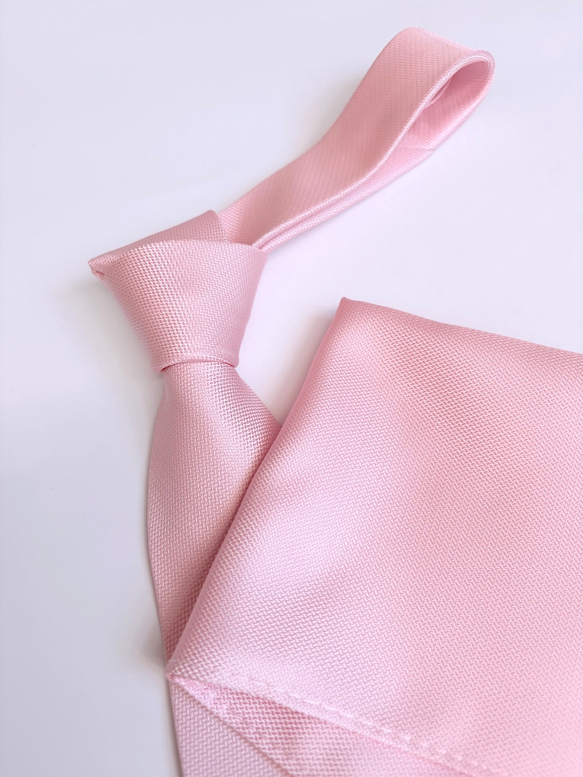 Light pink tie and pocket square set on a light background