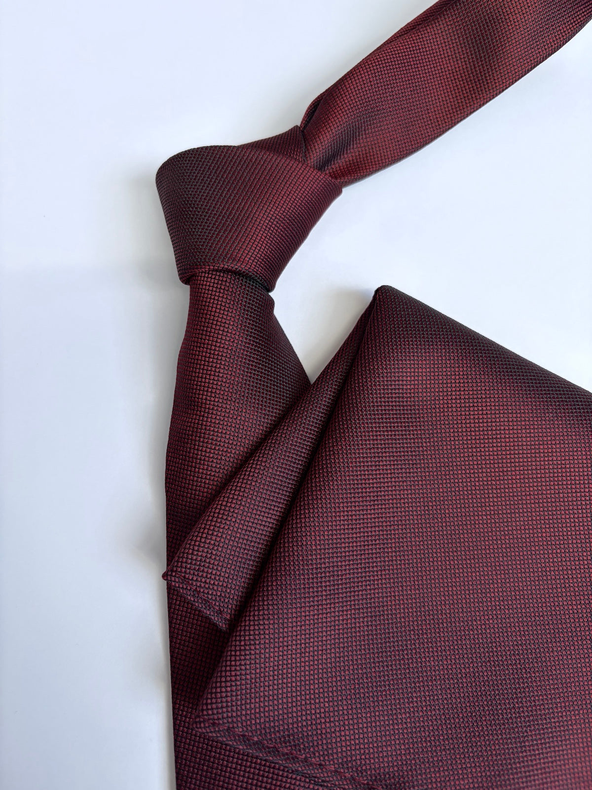 Dark red tie and pocket square on a white background