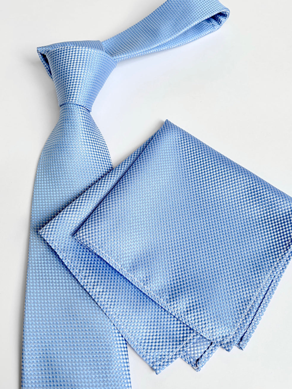 Light blue tie and matching pocket square on a white background